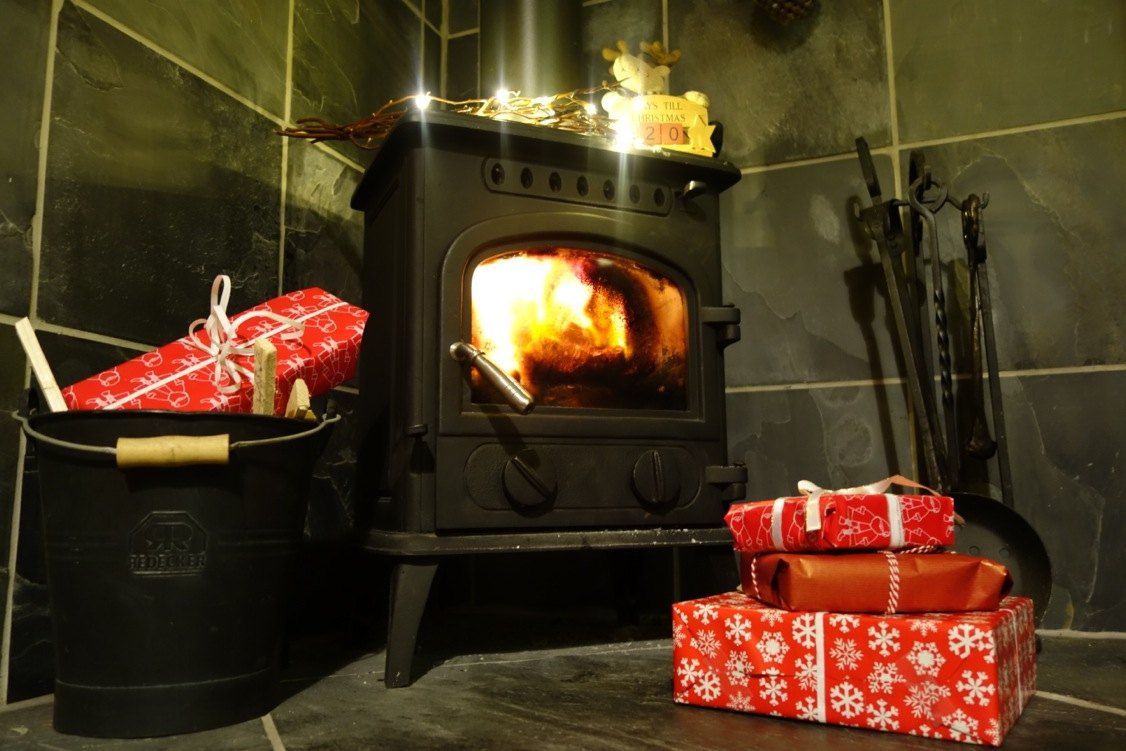 A woodburner, fairy lights and wrapped Christmas presents