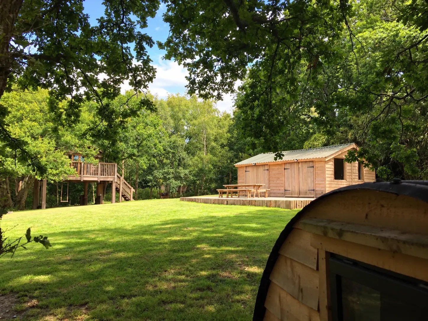The lawn with the Den’s covered seating and the treehouses beyond