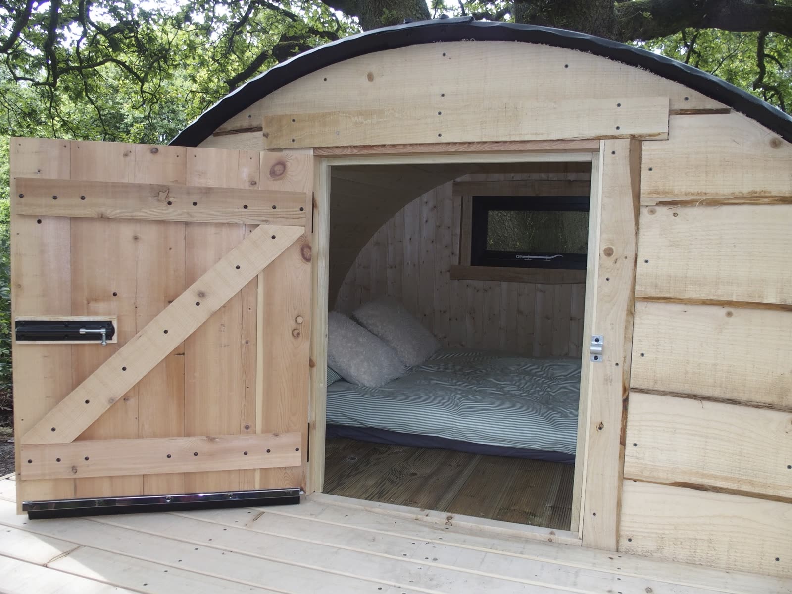 The Pig Pod with its door open, a bed inside
