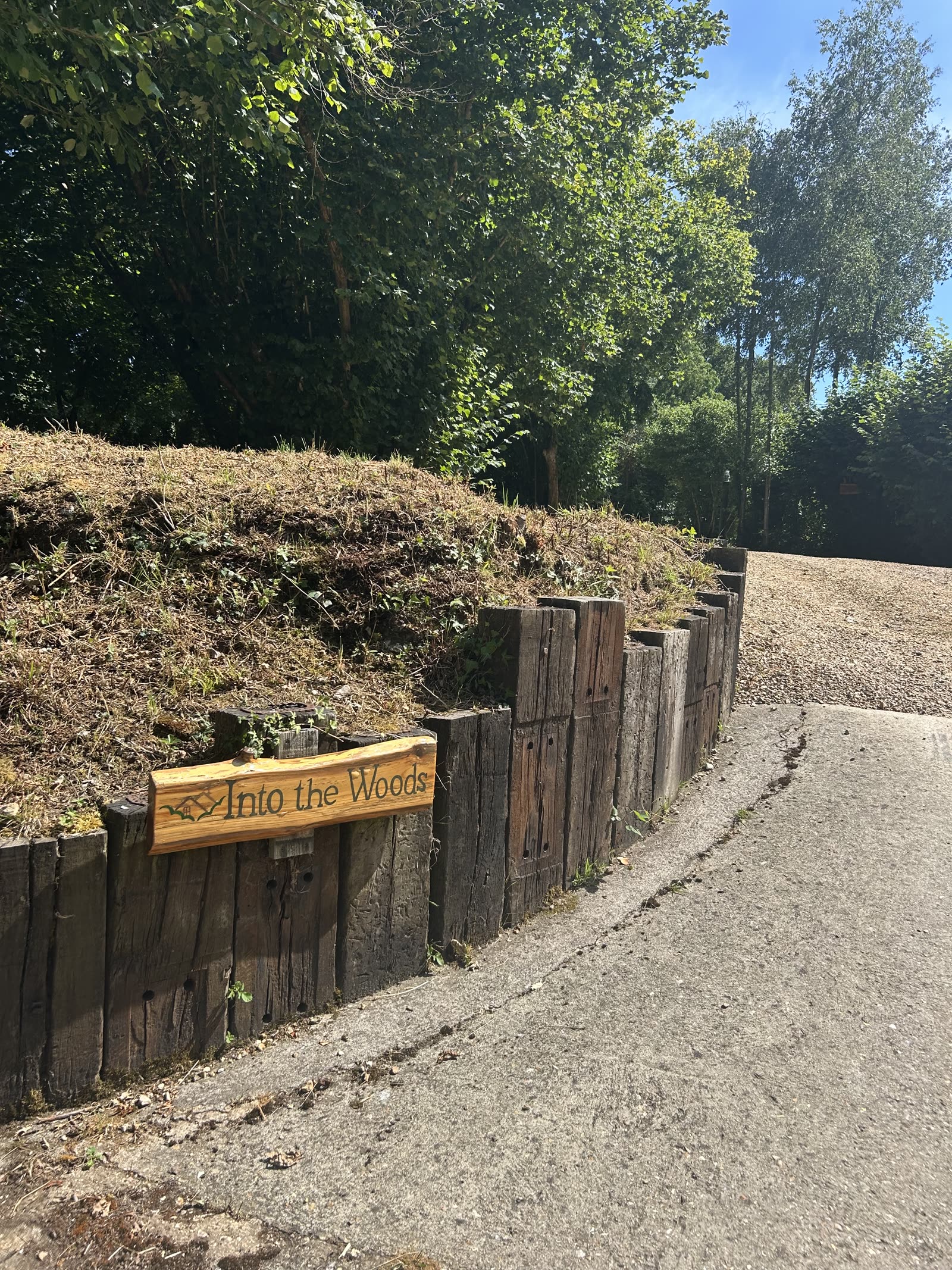 The Into the Woods sign beside the timber-lined drive